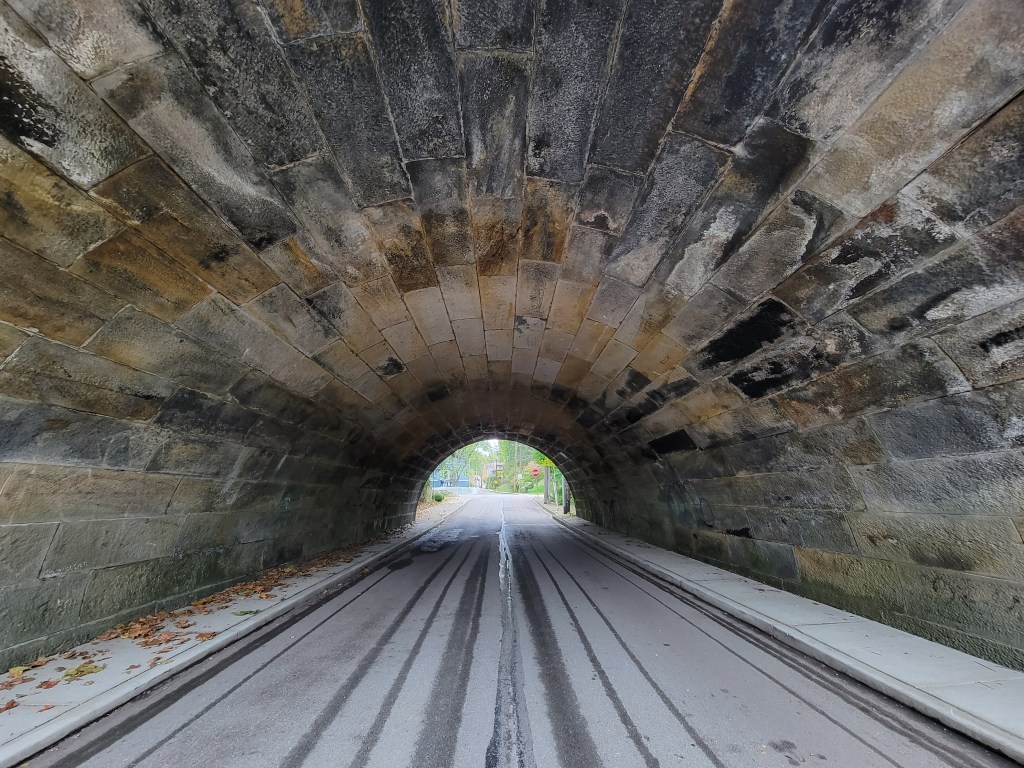 Tunnel Vision by Beverlee Blair, view from inside a wide stone tunnel looking out toward daylight, with the path receding into the distance.