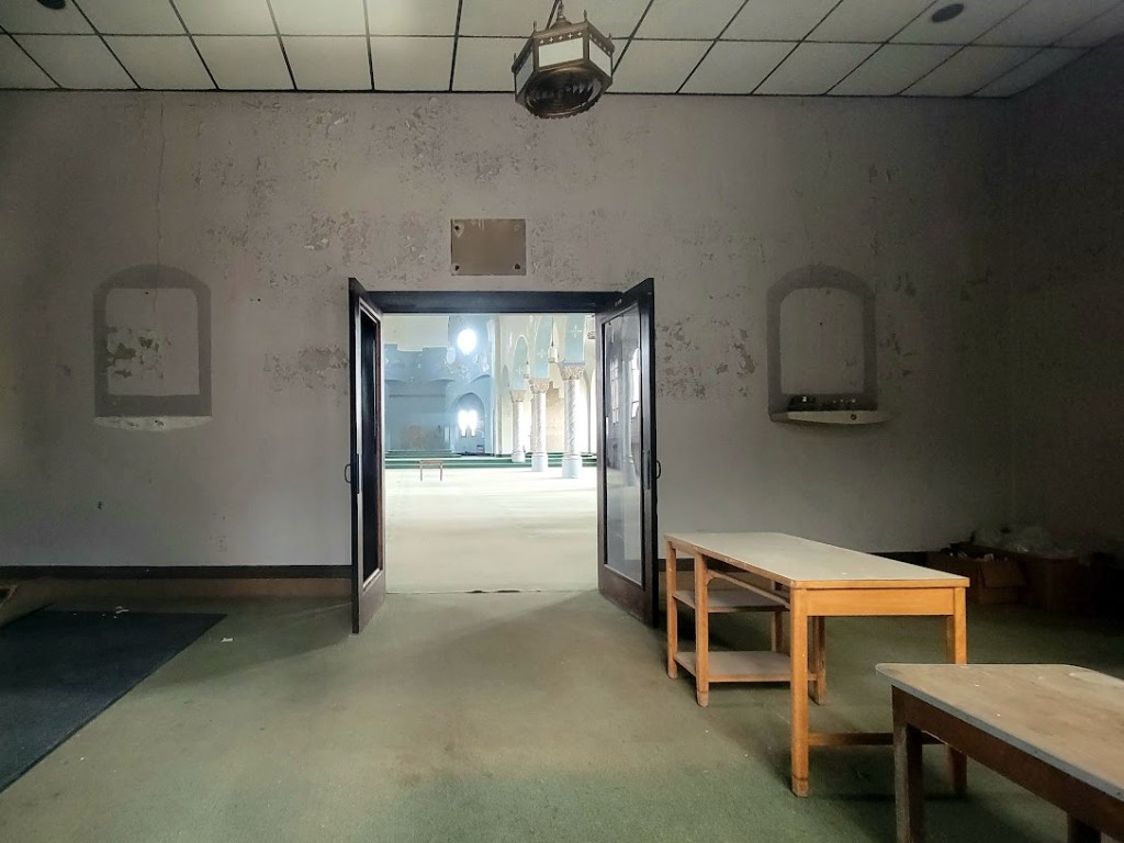 Worn interior room opening into a brighter ornate hall