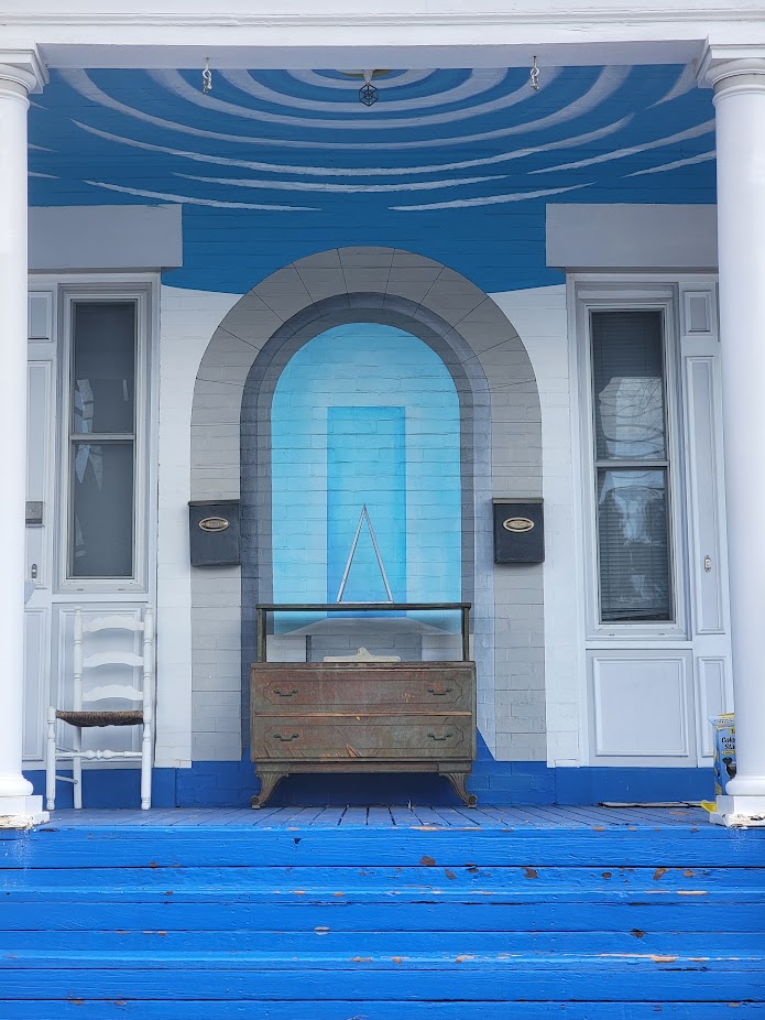 Blue painted porch with mural arch and vintage dresser