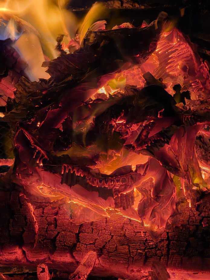 Close-up of glowing embers and burning wood in a fire.